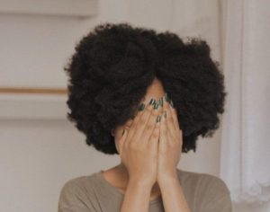 Woman hides her face with the palm of her hands