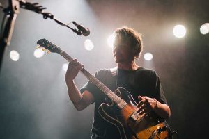 Musician playing guitar and singing on stage