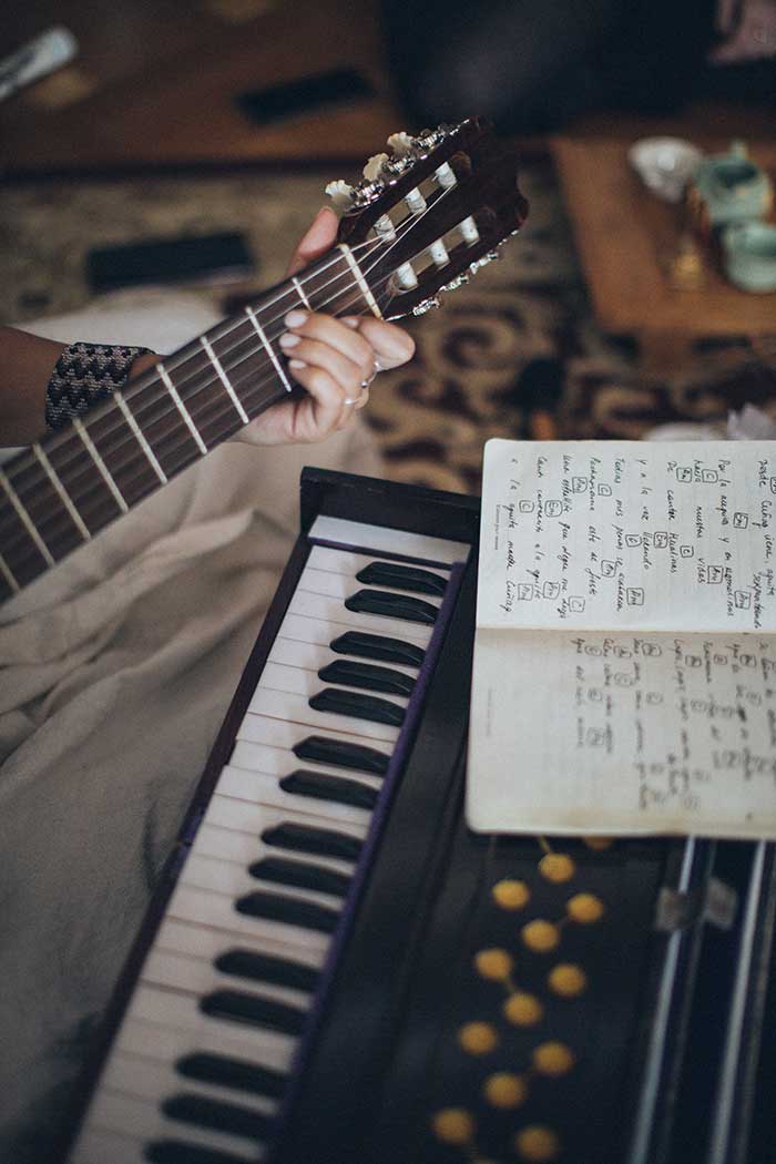 Musician composing on guitar. Keyboard shown on the back.